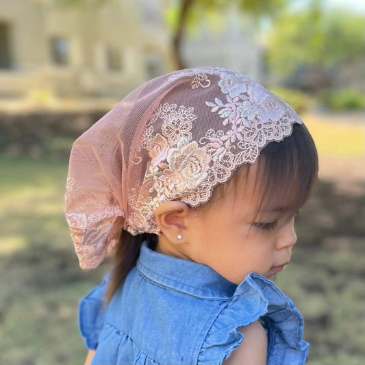 Baby wearing peach lace veil with rose embroidery. The toddler mantilla is perfect for Traditional Catholic Christian Mass