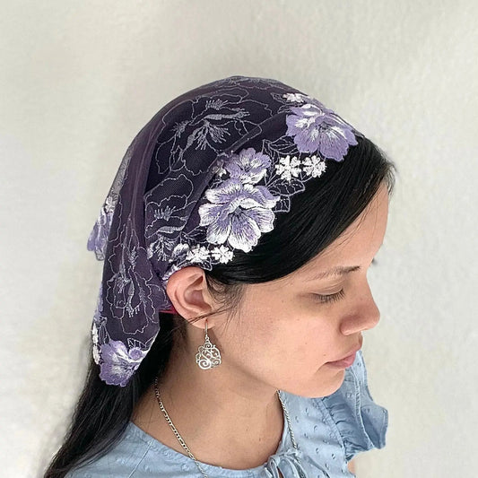 Girl wearing a purple chapel veil with floral embroidery. The small Traditional Catholic Christian Mass mantilla is tied on.