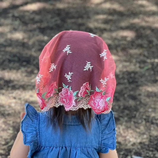 Rear view of a baby's head and a stunning red pink embroidered Christian chapel veil.