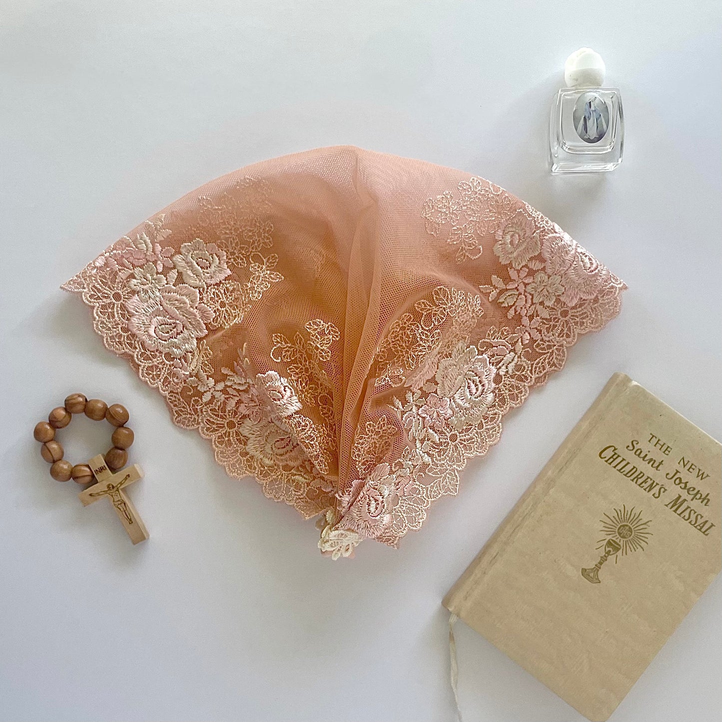 Peach-colored lace veil with rose embroidery. The baby or toddler mantilla is perfect for Traditional Catholic Christian Mass