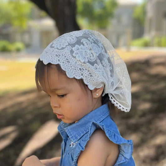 Child wearing ivory colored lace chapel veil.