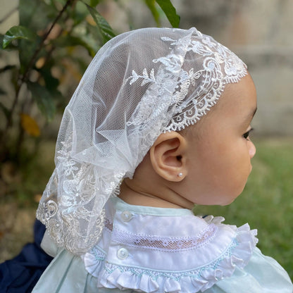 Infant wearing an ivory embroidered lace chapel veil for Traditional Catholic Mass.