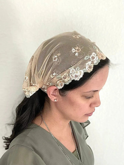 Girl wearing a beige lace embroidered traditional Catholic mass veil bandana.