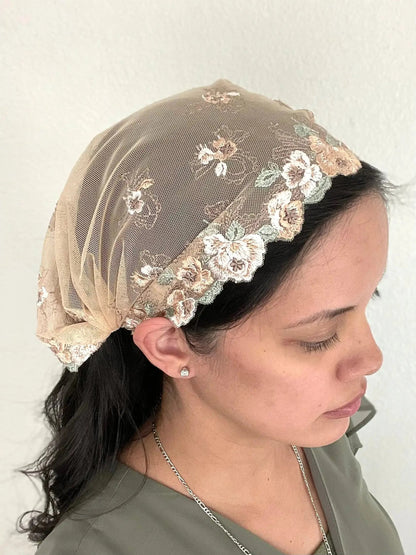 Woman wearing a beige lace embroidered traditional Catholic mass veil headscarf.
