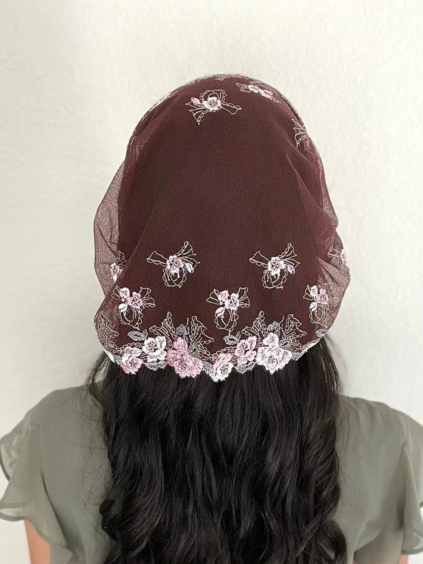Back view of woman wearing a burgundy lace embroidered traditional Catholic mass veil headscarf.