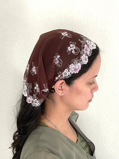 Woman wearing a burgundy lace embroidered traditional Catholic mass veil headscarf.