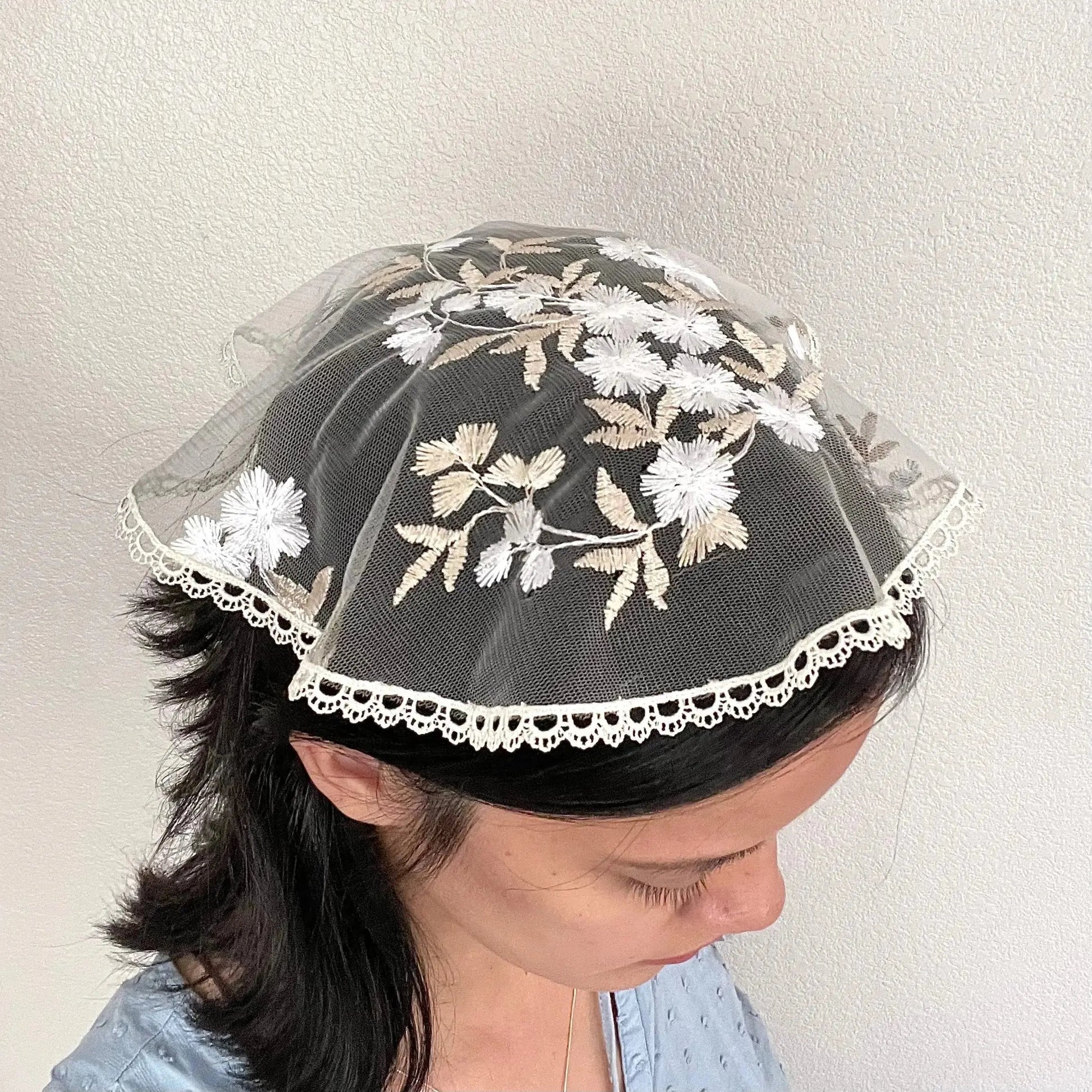 Girl in a traditional white gold circular cap veil with embroidered floral lace.