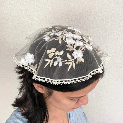 Girl in a traditional white gold circular cap veil with embroidered floral lace.