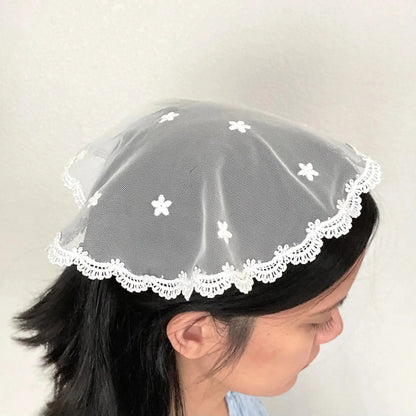 Girl in a traditional ivory circular cap veil with embroidered floral lace. 