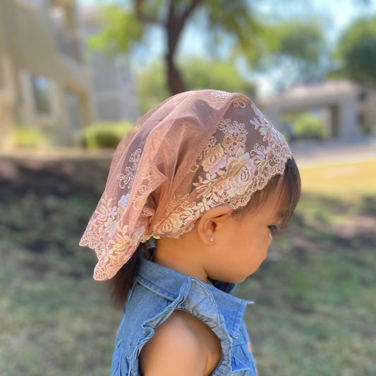 Baby wearing peach lace veil with rose embroidery. The toddler mantilla is perfect for Traditional Catholic Christian Mass