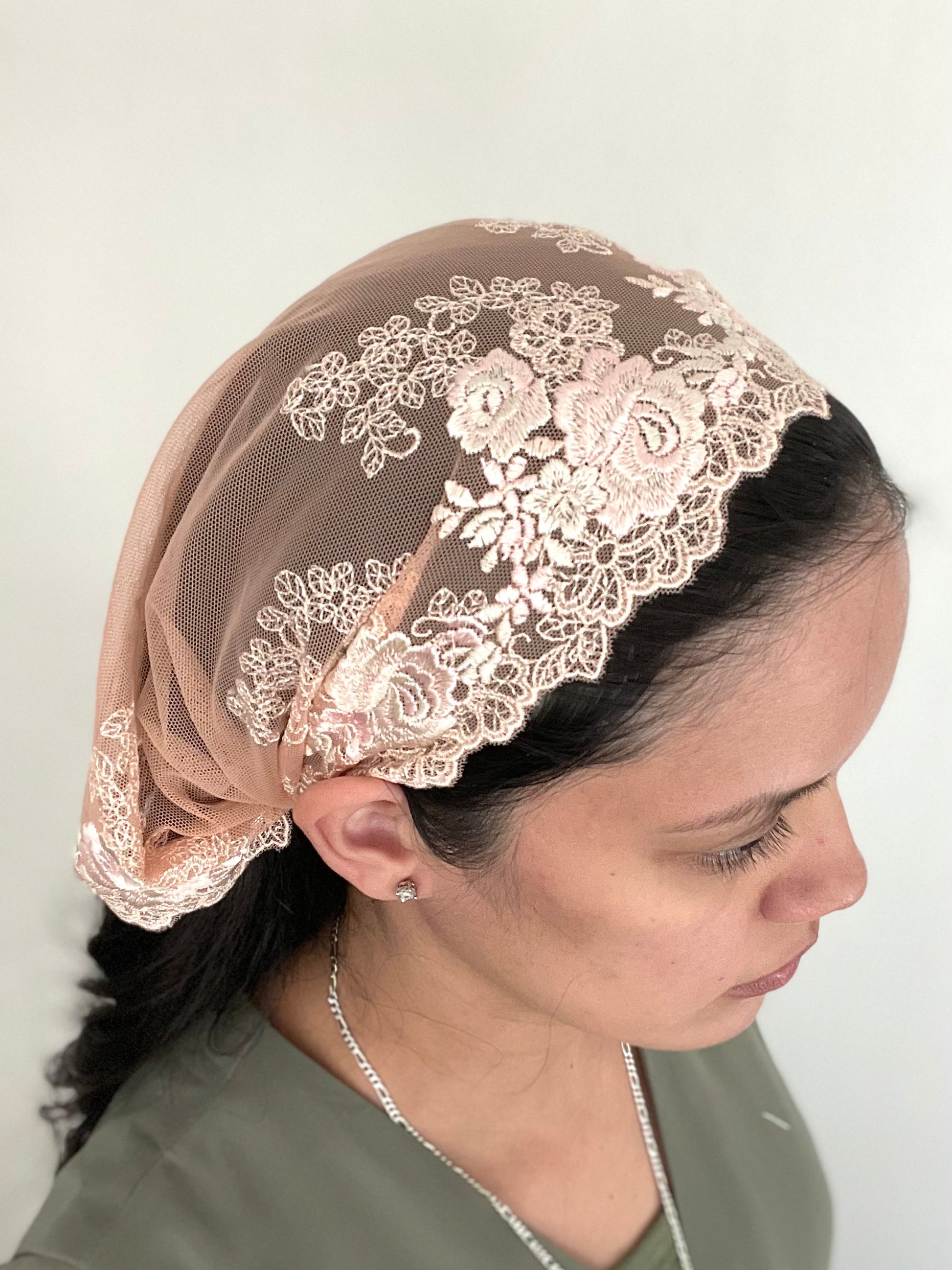 Girl wearing a lace chapel veil with rose embroidery. The small peach Traditional Catholic Christian Mass mantilla has ties