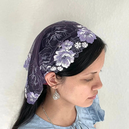 Girl wearing a purple chapel veil with floral embroidery. The small Traditional Catholic Christian Mass mantilla is tied on.