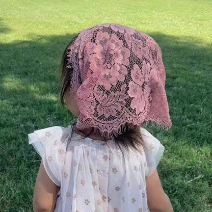 Baby wearing a dark pink lace traditional catholic mass veil. 