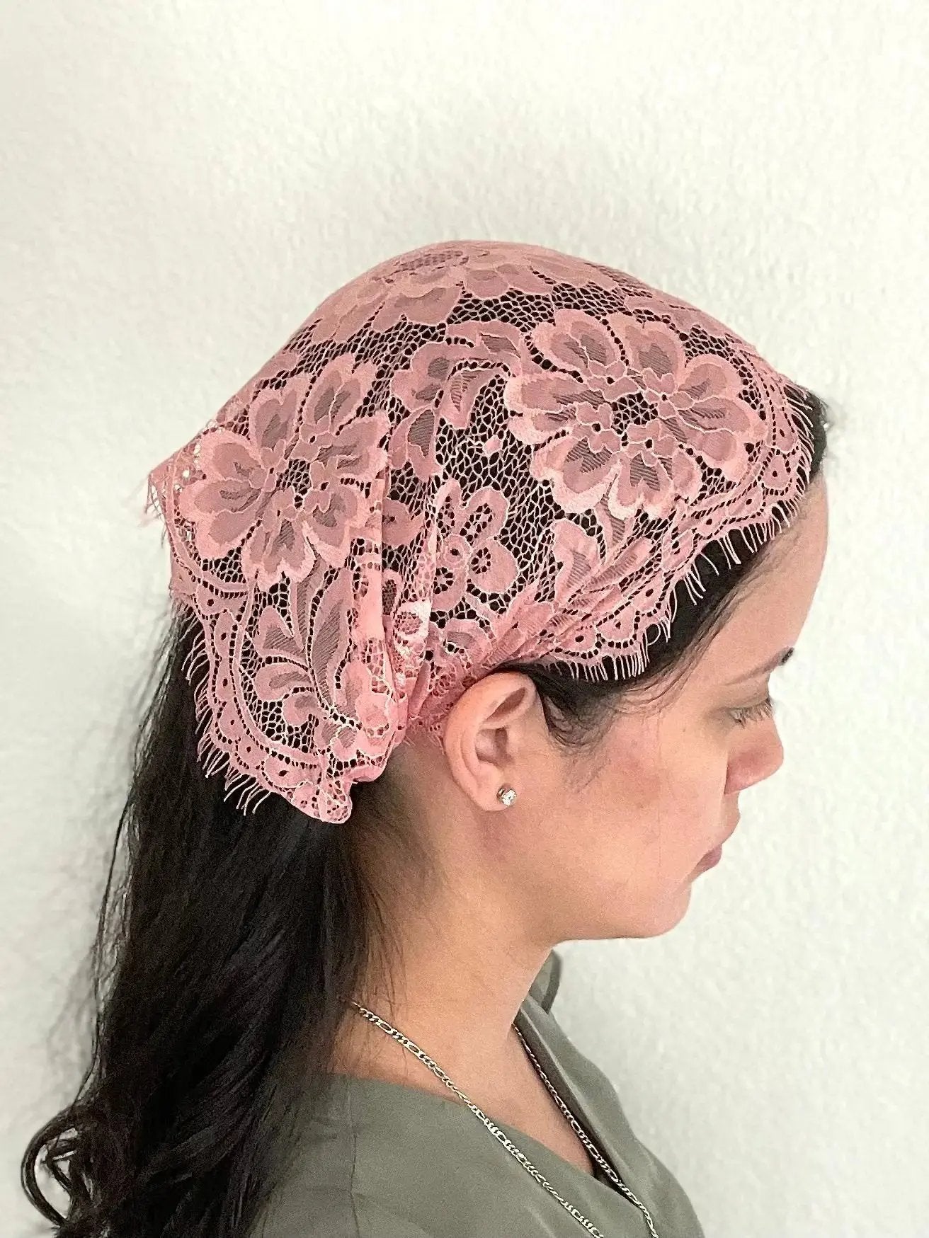 Girl wearing a traditional dark pink floral eyelash lace Catholic chapel veil headwrap.
