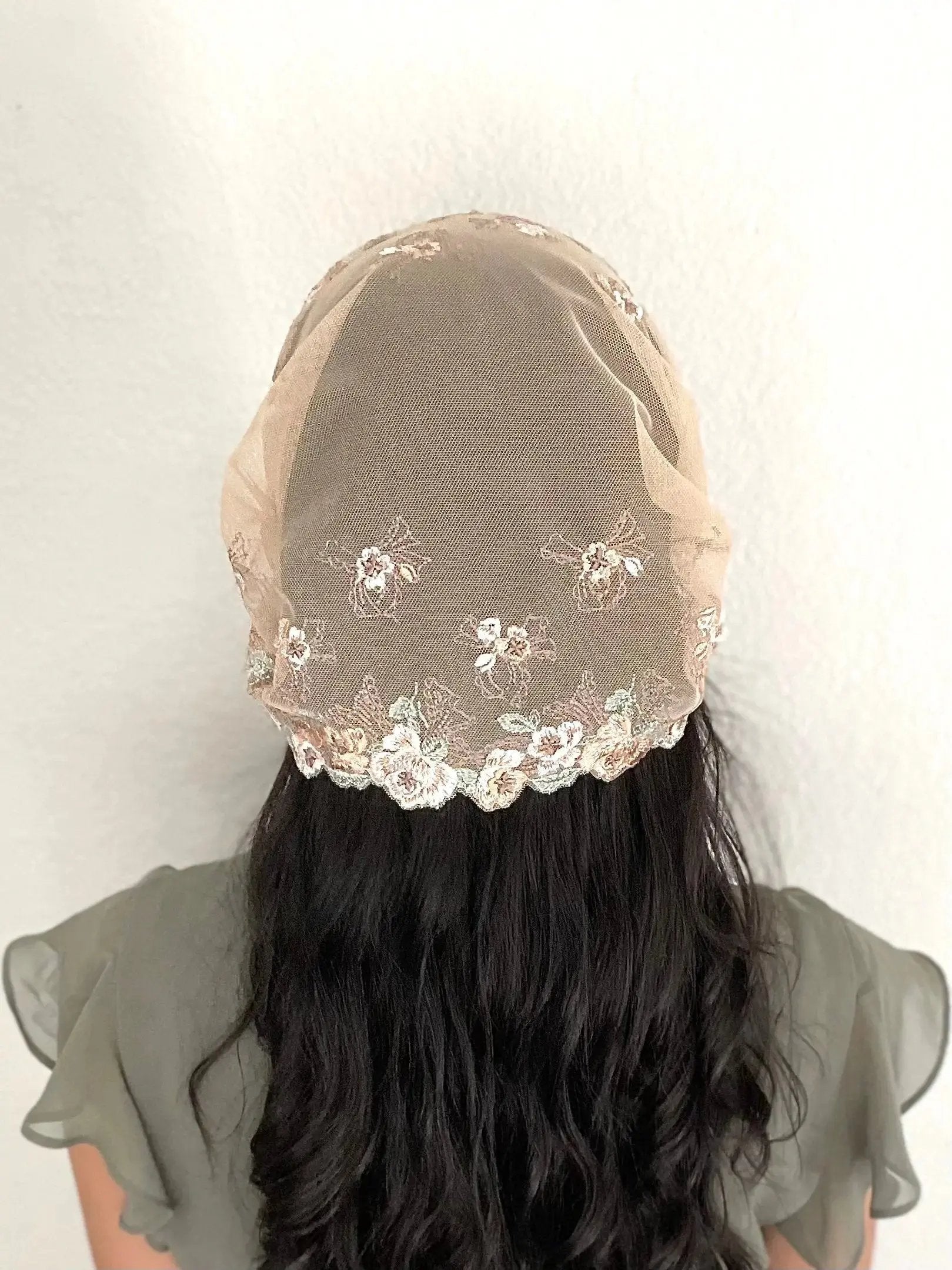 Back view of girl wearing a light brown lace embroidered traditional Catholic mass veil headscarf.