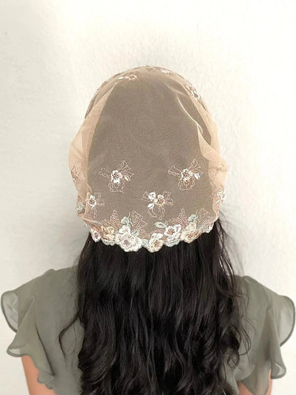 Back view of girl wearing a light brown lace embroidered traditional Catholic mass veil headscarf.
