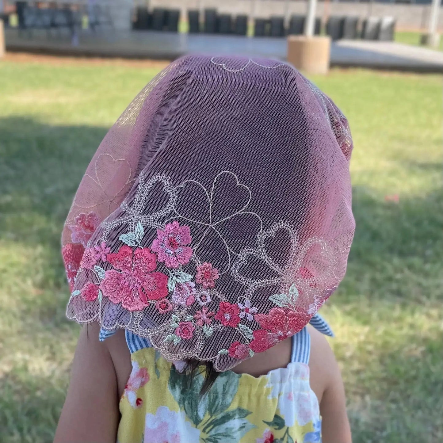 The back of a toddler shows the beautiful lace embroidery on a floral chapel veil.