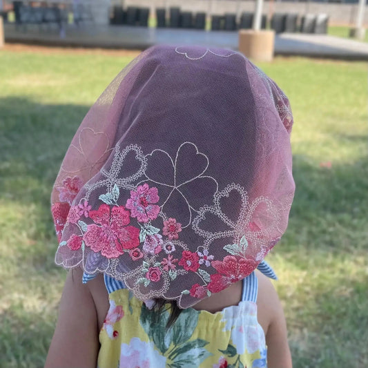 The back of a toddler shows the beautiful lace embroidery on a floral chapel veil.