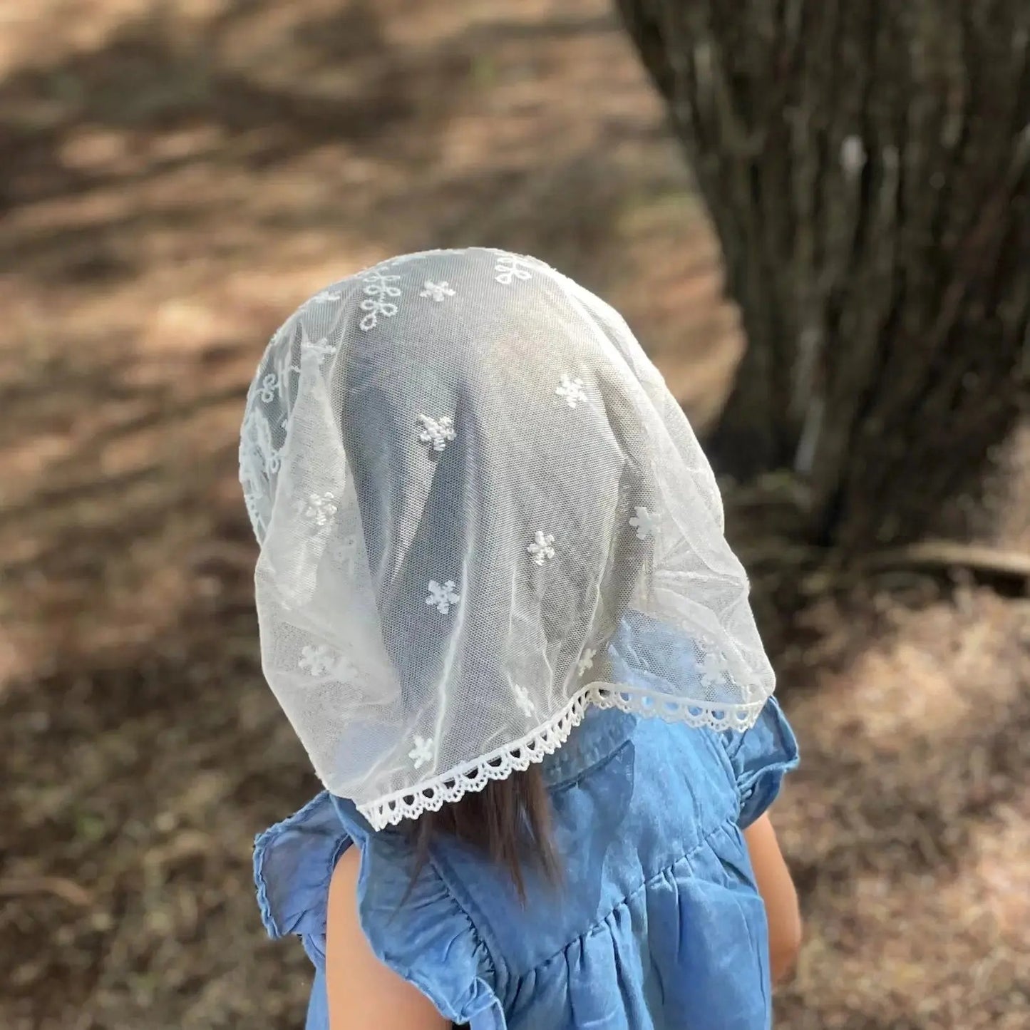 Back view focusing on the delicate embroidered lace of an infant's white chapel veil.
