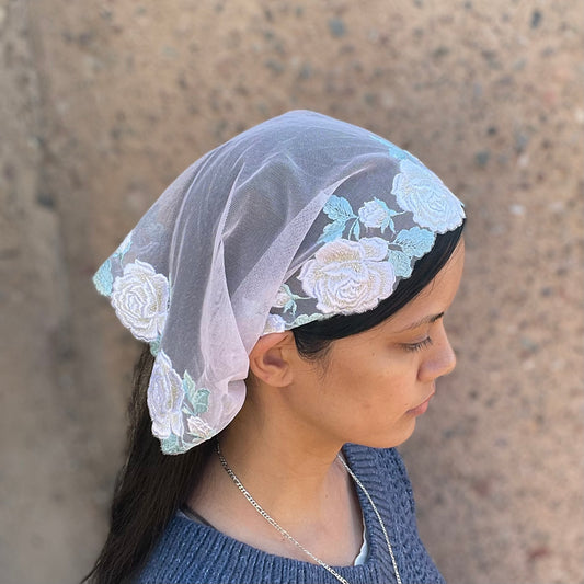 Girl wearing an ivory pink chapel veil with rose embroidery. The small Traditional Catholic Christian Mass mantilla has ties
