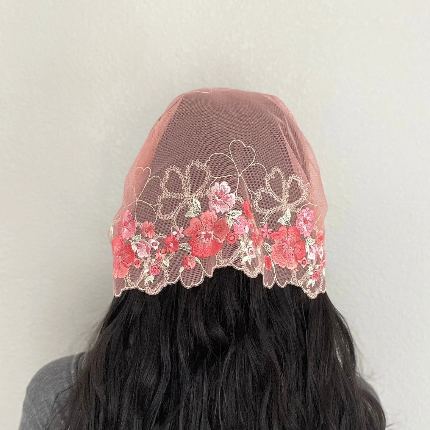 Back view of girl wearing an embroidered pink lace traditional chapel veil.
