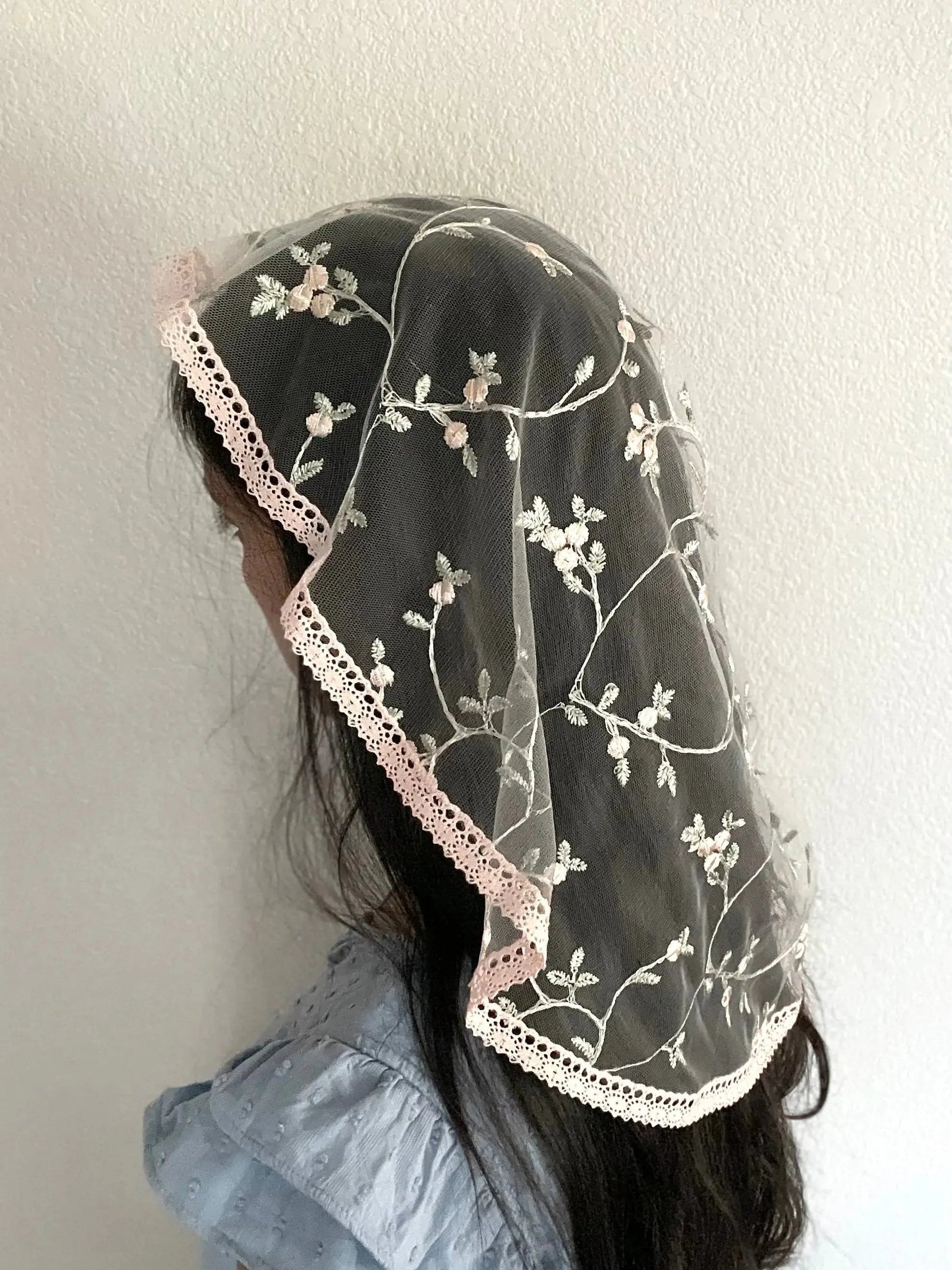 Girl wearing a pink princess veil for a Catholic mass or prayer service.