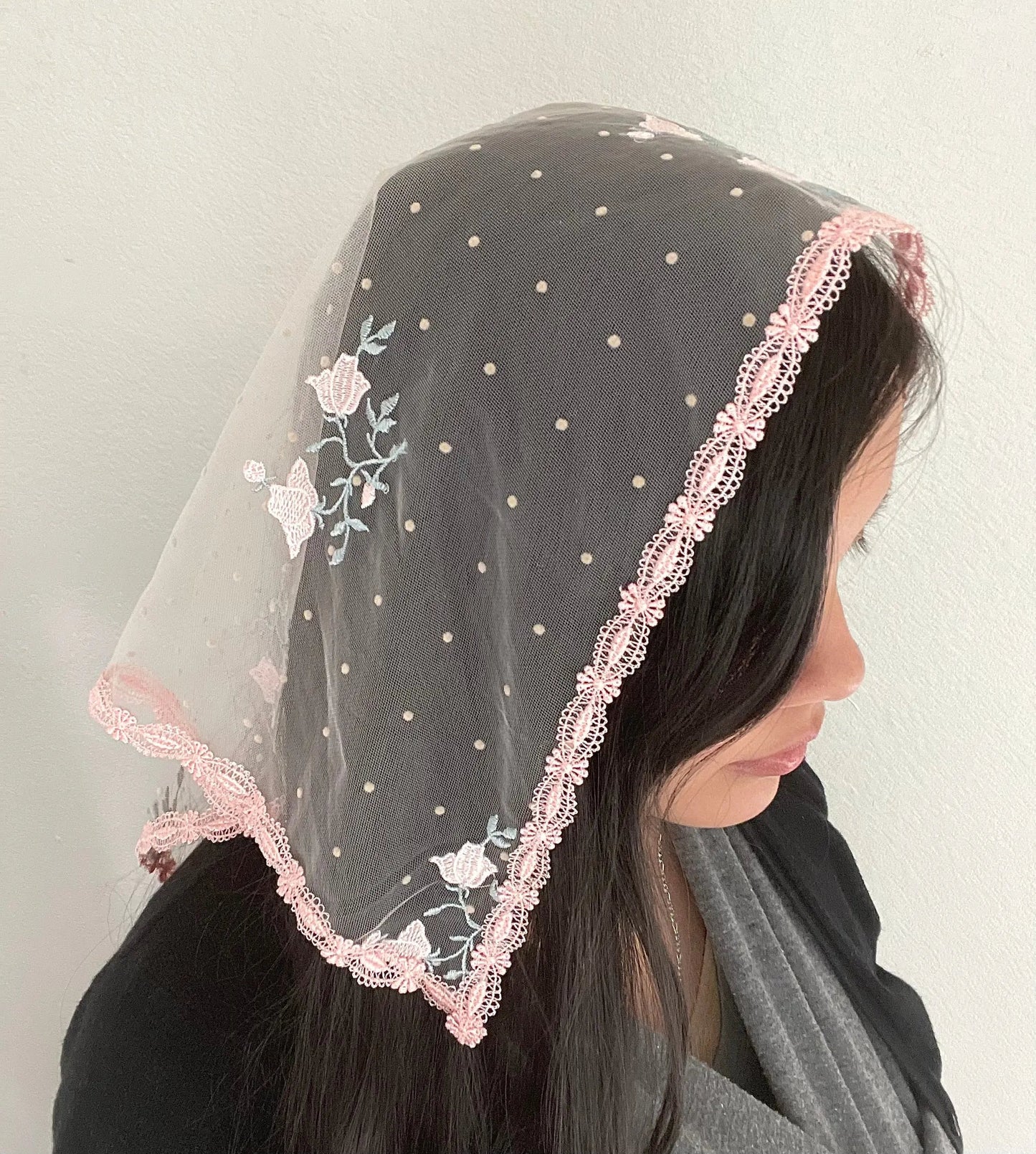 Girl wearing a pink embroidered lace triangle veil for Traditional Catholic mass.
