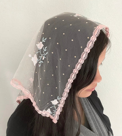 Girl wearing a pink embroidered lace triangle veil for Traditional Catholic mass.