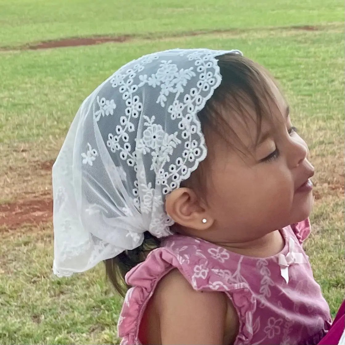 Baby in a white embroidered lace catholic chapel veil for baptism.
