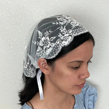 Girl wearing an ivory lace embroidered traditional Christian mass veil headscarf for Holy Communion.