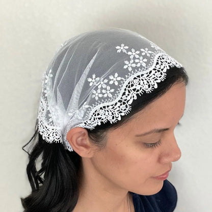 Girl wearing a one size white lace embroidered Catholic mass chapel veil.