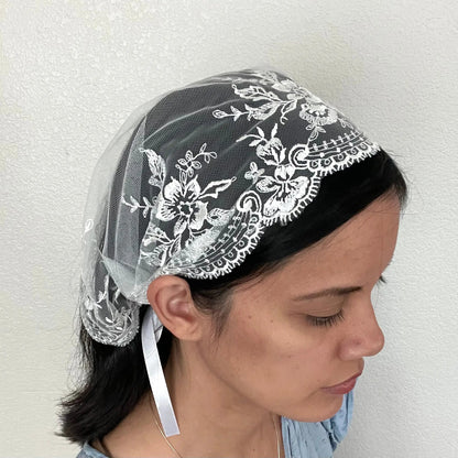Girl wearing a beautiful white embroidered lace chapel veil kerchief. 