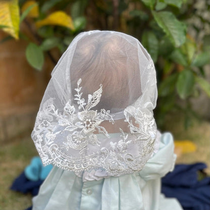 Infant wearing an ivory embroidered lace chapel veil for Traditional Catholic Mass.
