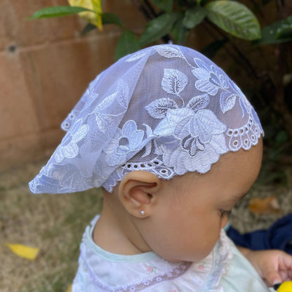 Infant wearing a traditional chapel veil of intricate ivory lace embroidery for Catholic baptism Mass