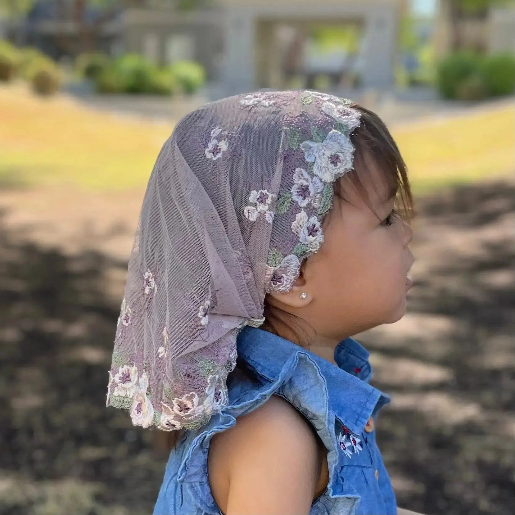 Baby wearing a soft purple embroidered lace chapel veil, perfect for Traditional Catholic Mass.