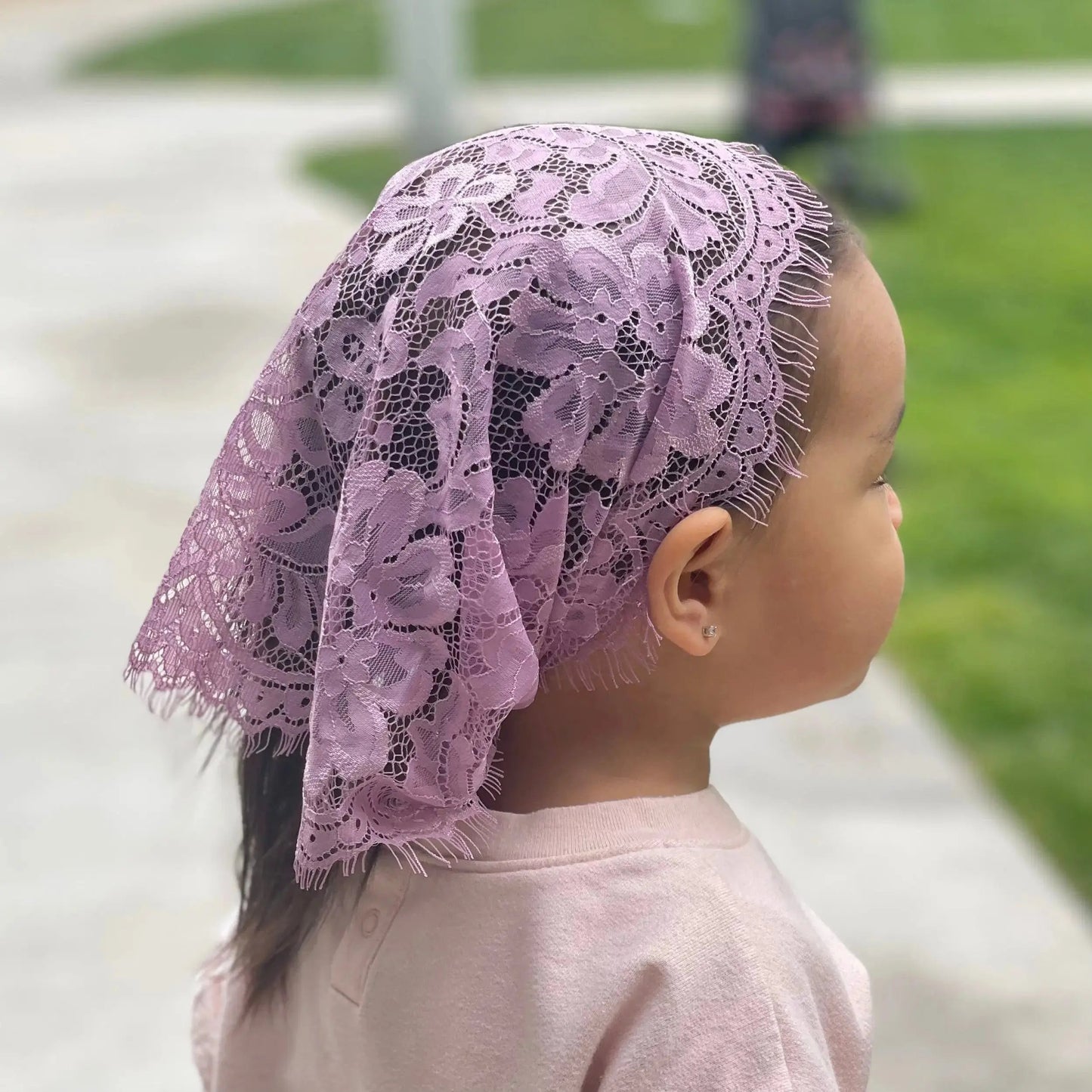 Baby wearing a soft purple lace traditional catholic mass veil. 