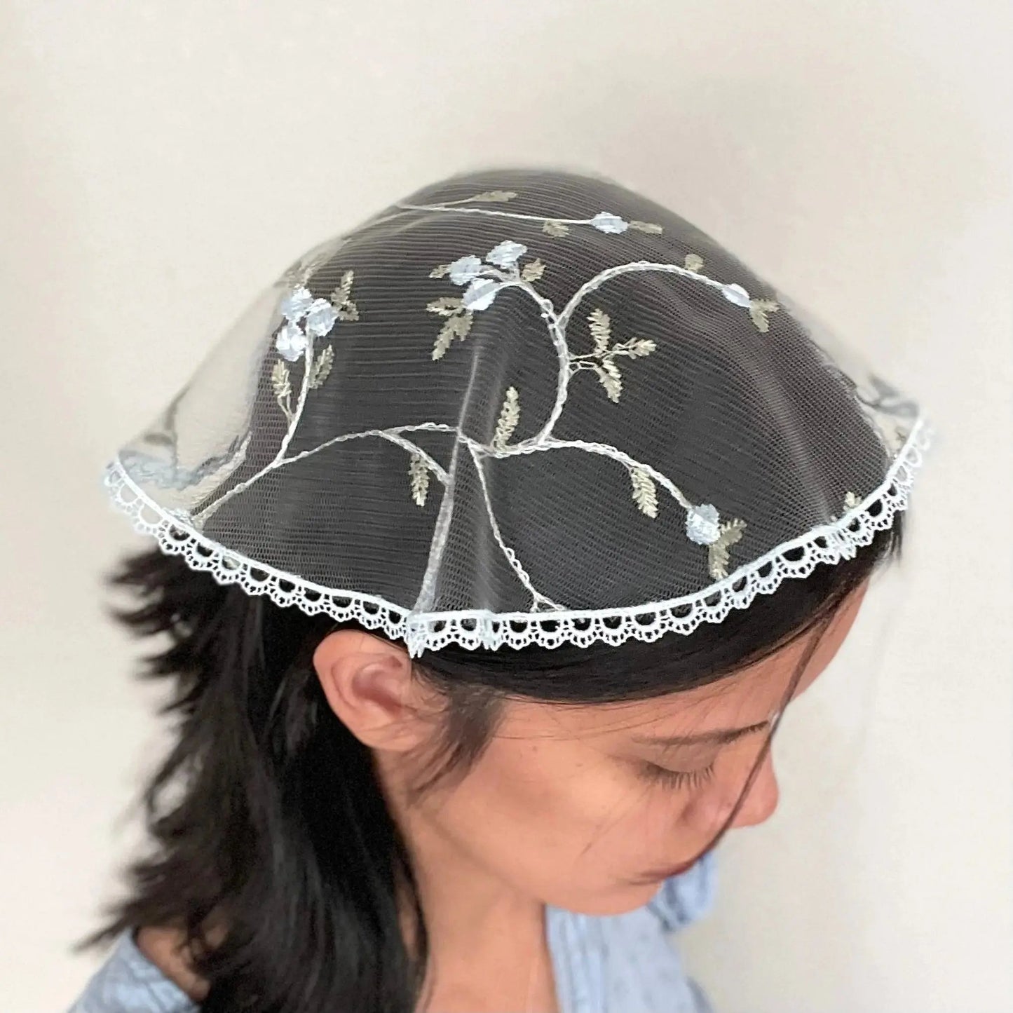 Girl in a traditional floral blue circular cap veil with embroidered lace.