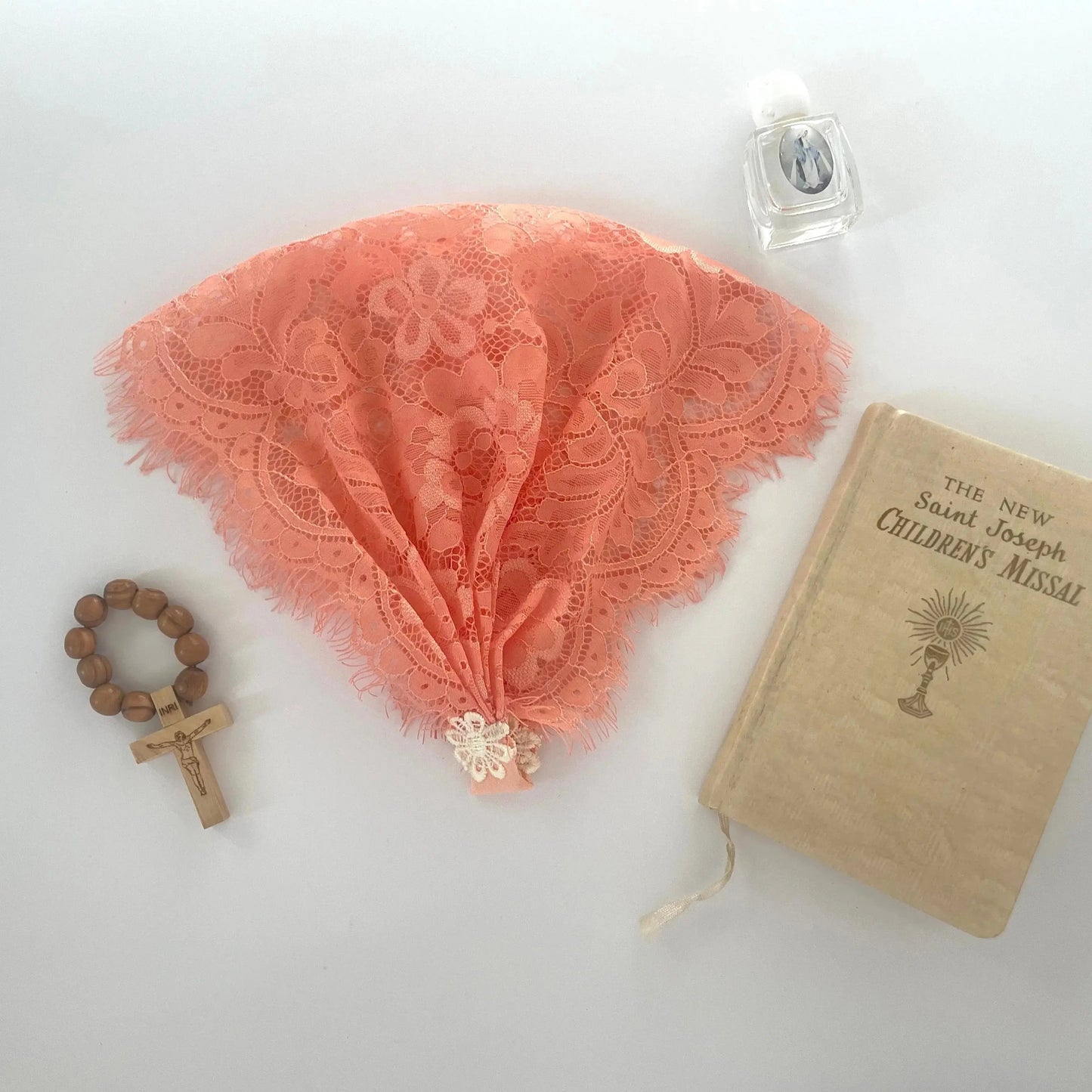 Orange floral eyelash lace newborn veil for a traditional Catholic prayer service.