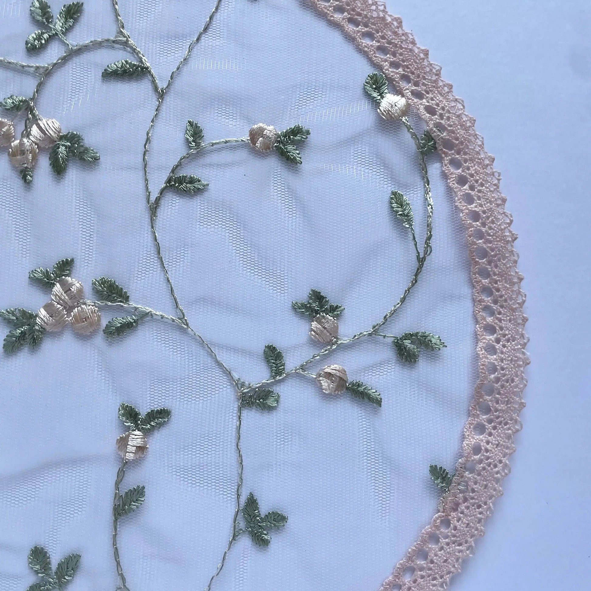 Light pink embroidered floral design on tulle lace fabric.