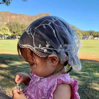 Infant wearing light pink lace veil with floral embroidery. The mantilla is perfect for Traditional Catholic Christian Mass