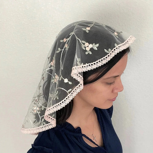 Girl wearing a pink floral embroidered lace oval veil for Catholic mass.