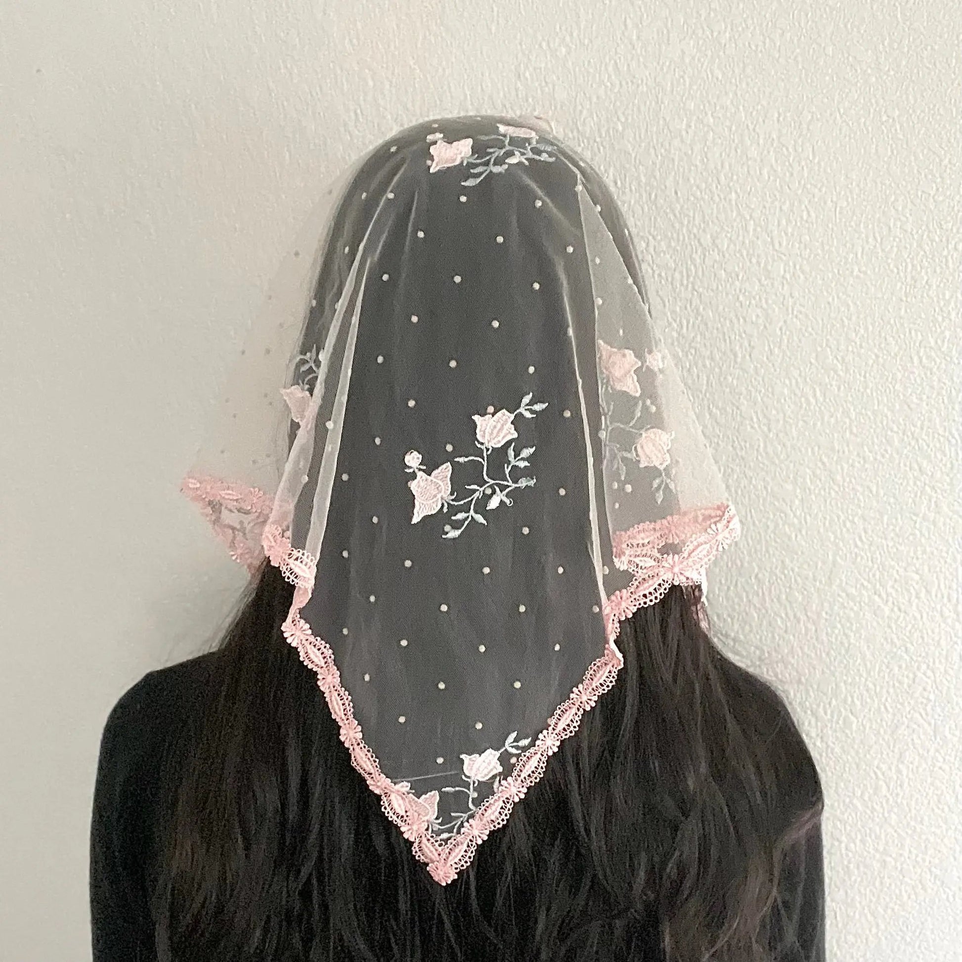  Back view of girl wearing a pink rose embroidered lace triangle chapel veil for Catholic mass.
