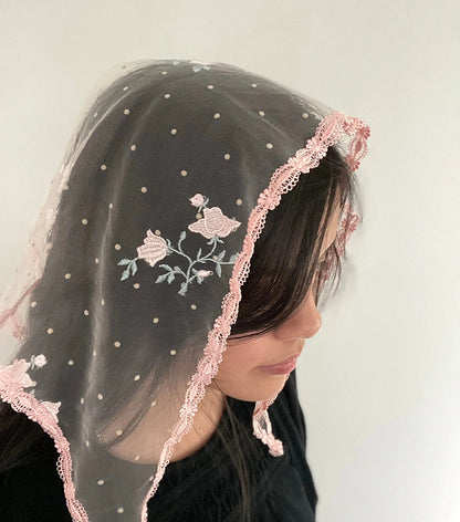 Girl wearing a pink roses embroidered lace triangle veil for Catholic mass.