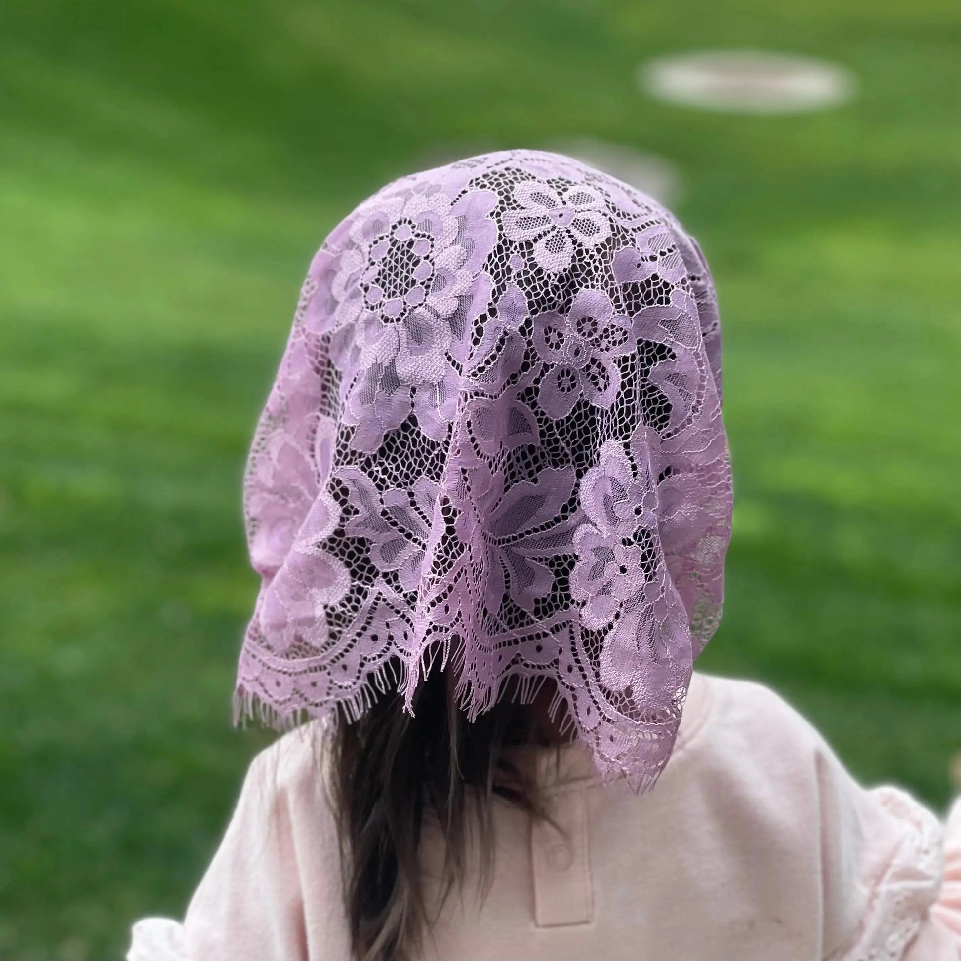 Back view of toddler wearing a lace traditional catholic mass veil. 