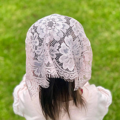 Back view of a toddler wearing a light pink eyelash lace chapel veil.