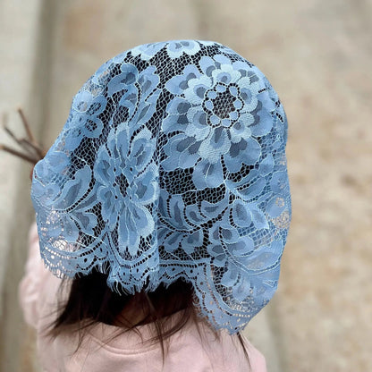 Infant wearing a blue prayer chapel veil with eyelash lace.