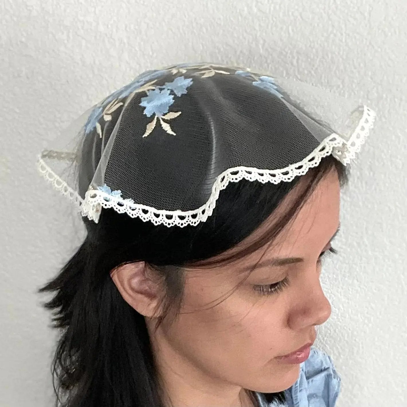 Girl wearing a blue and pale gold embroidered lace cap chapel veil for Traditional Catholic mass.