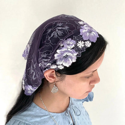 Woman wearing a purple lace chapel veil with white rose embroidery. The small Traditional Catholic Christian Mass mantilla
