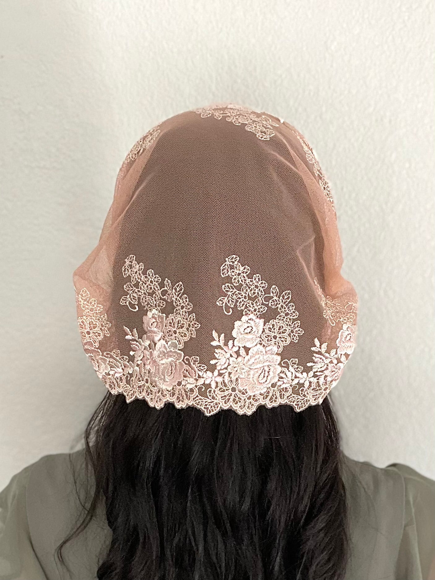 Girl wearing a lace chapel veil with peach rose embroidery. The small Traditional Catholic Christian Mass mantilla has ties