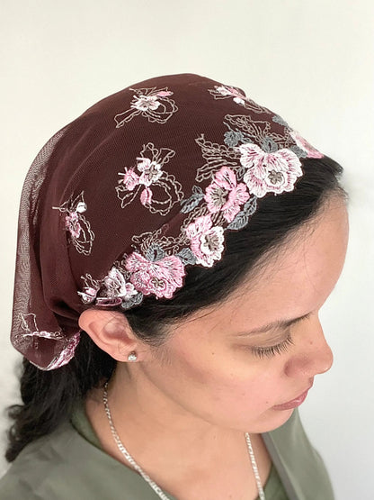 Girl wearing a burgundy lace embroidered traditional Catholic mass veil headscarf.